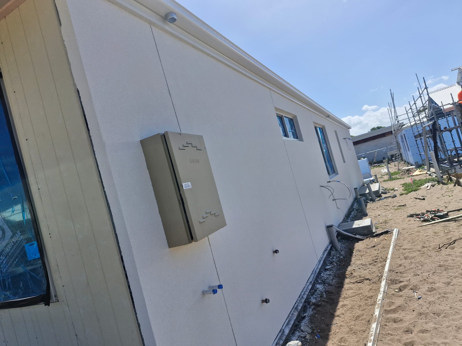Long light-coloured rendered side wall with service penetrations